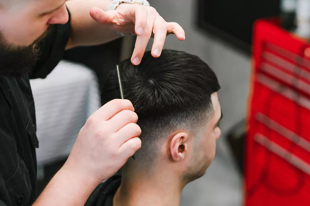 Mann, dessen Haare vom Friseur abgeteilt werden