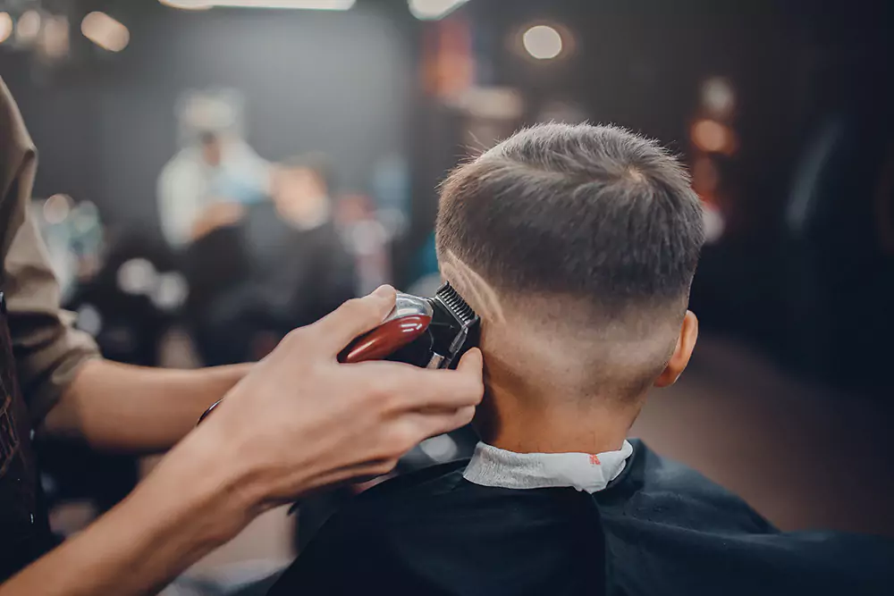 Junge, dem vom Friseur ein Muster in die Haare rasiert wird