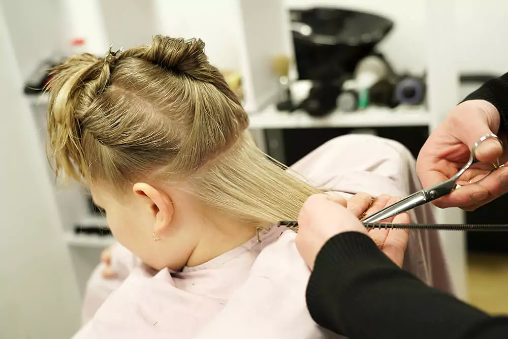 Kleines Mädchen beim Friseur, das einen Haarschnitt bekommt